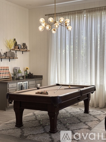 A pool table is in the middle of a room with a light hanging above it.