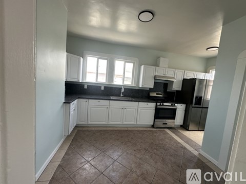 A kitchen with white cabinets and a tiled floor.
