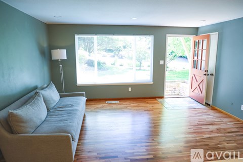 A living room with a grey couch and a lamp on the side table.
