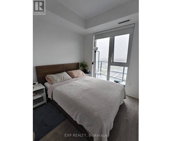 A bedroom with a large bed and a window overlooking the street.