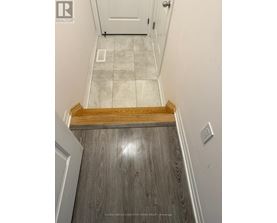 A hallway with a wooden floor leading to a white door.