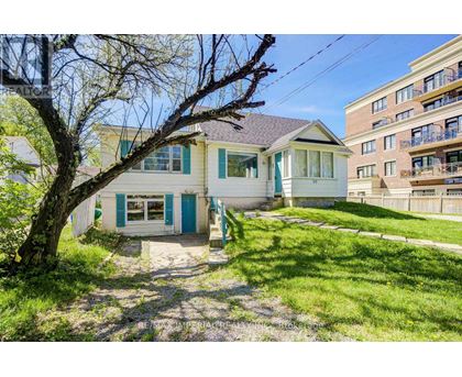 A small house with a blue door is surrounded by a grassy area and a tree.