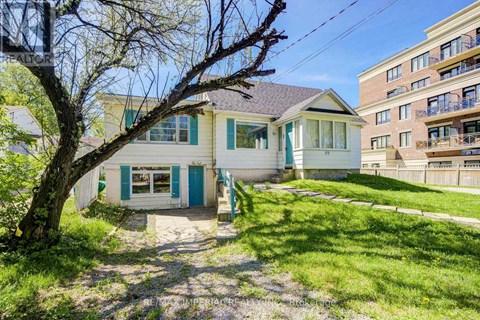 A small house with a blue door is surrounded by a grassy area and a tree.