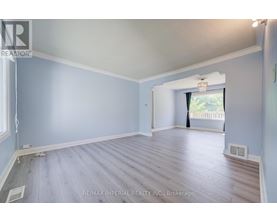 A spacious room with light blue walls and wooden flooring.