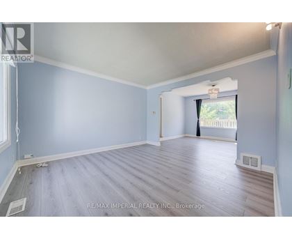 A spacious room with light blue walls and wooden flooring.