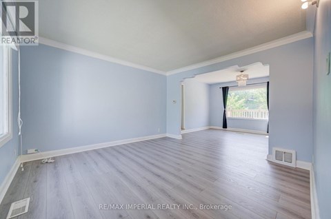 A spacious room with light blue walls and wooden flooring.