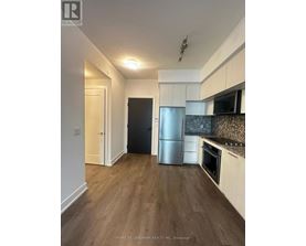 A kitchen with a refrigerator, oven, and microwave.