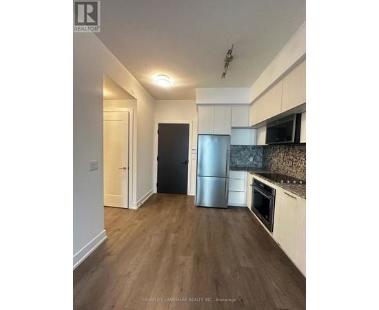 A kitchen with a refrigerator, oven, and microwave.