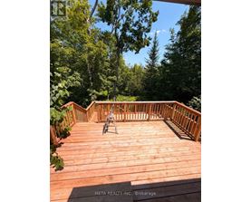 A wooden deck with a chair and a table in the middle of it.