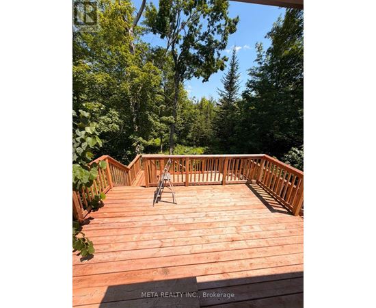 A wooden deck with a chair and a table in the middle of it.