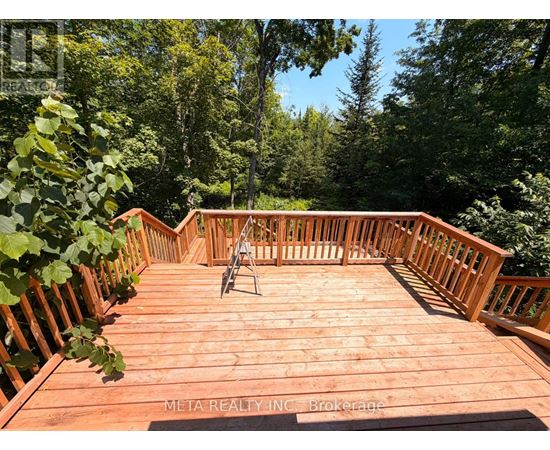 A wooden deck with a railing and a chair.