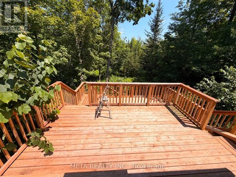 A wooden deck with a railing and a chair.