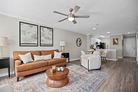 A living room with a brown couch and a ceiling fan.
