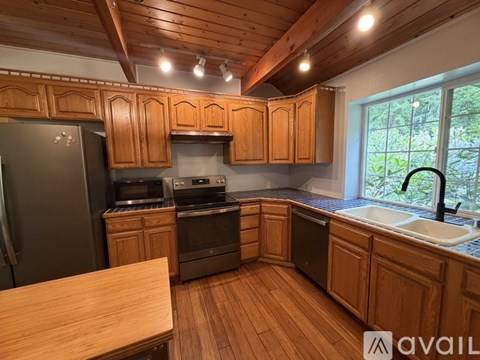 A kitchen with wooden cabinets and a black refrigerator.
