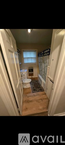 A narrow hallway with a rug and a window.