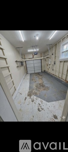 A room with a white ceiling and walls, a window, and a door.