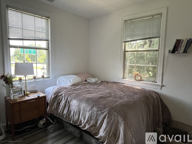A bedroom with a bed, nightstand, and window.