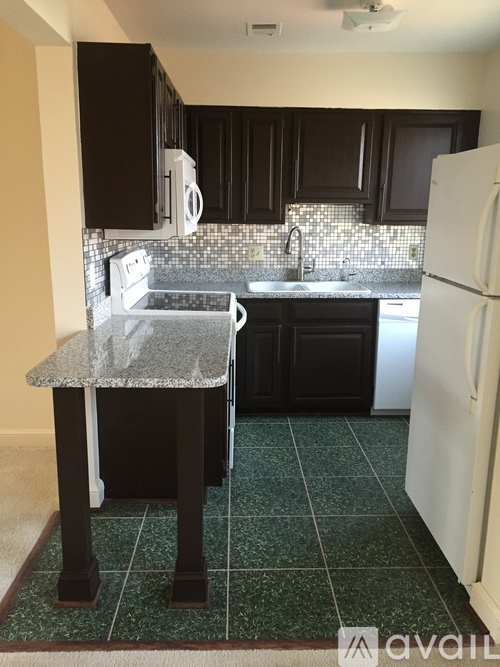 A kitchen with black cabinets and a white refrigerator.