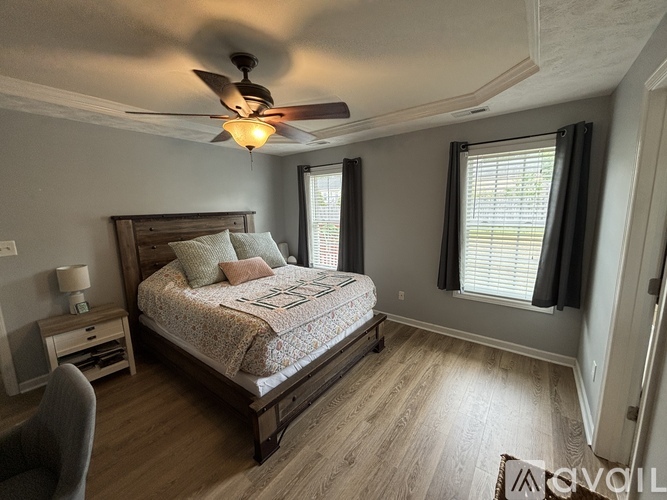 A bedroom with a bed, nightstand, chair, and window.