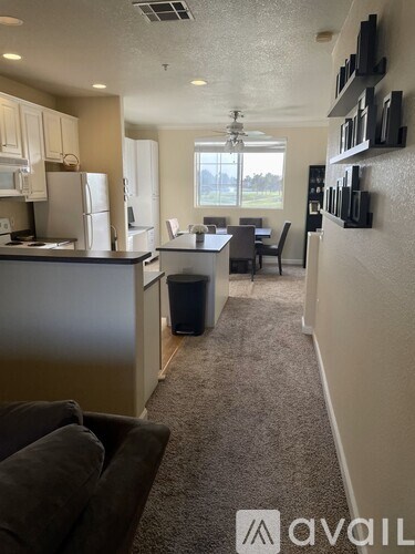 A living room with a couch and a kitchen area with a fridge and microwave.
