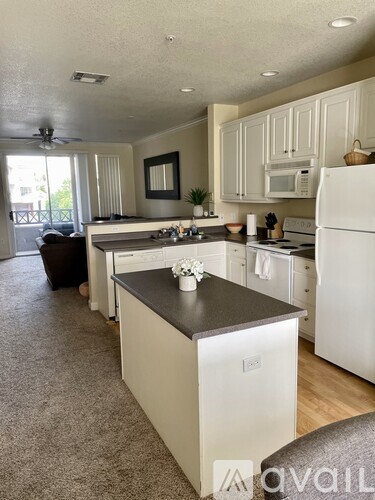A kitchen with white appliances and a black countertop.