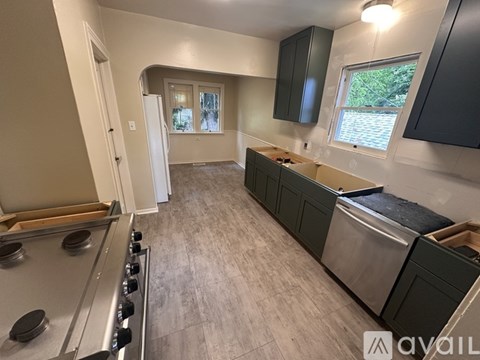 A kitchen with a stainless steel stove and dark grey cabinets.