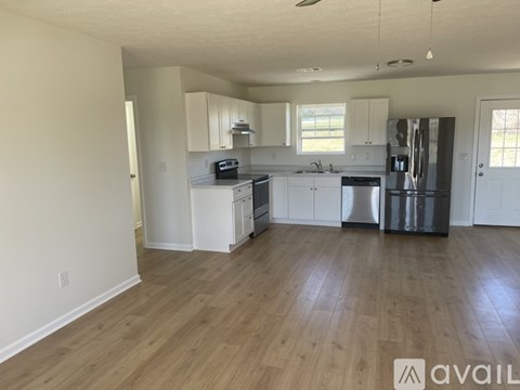 A kitchen with white cabinets and a wooden floor.