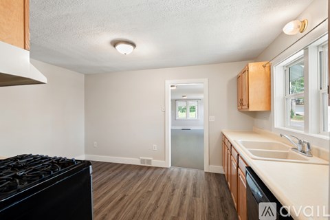 A kitchen with a black stove top oven and wooden cabinets.