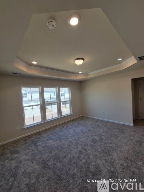 A room with a carpeted floor and a window overlooking a building.