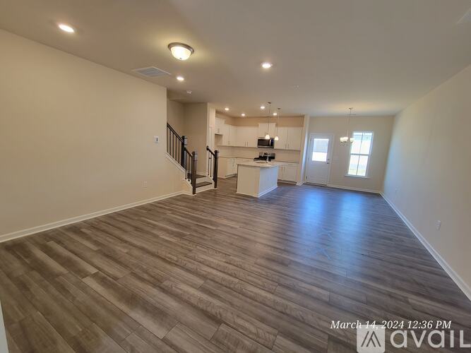A spacious room with wooden flooring and a staircase leading to another room.