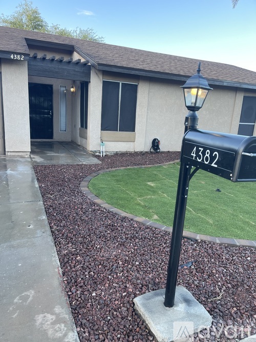 A black lamp post with the number 4382 on it stands in front of a house.