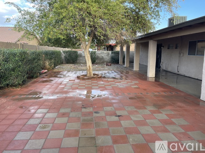 A courtyard with a tree and a building in the background.