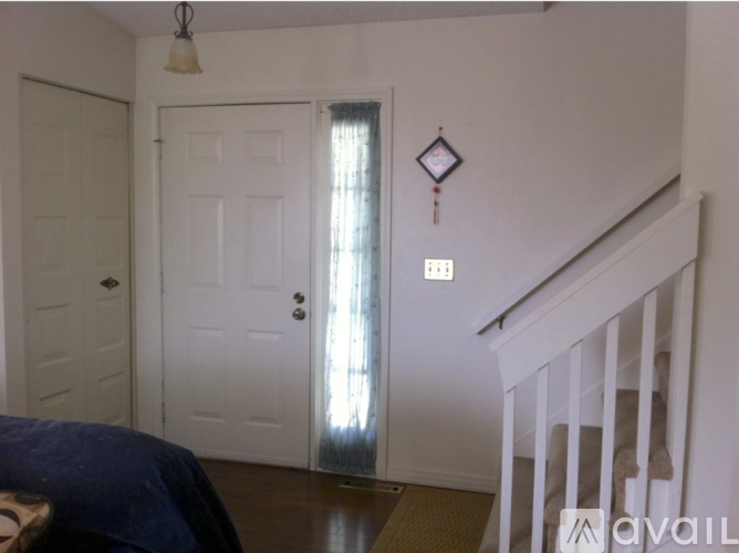 A bedroom with a bed, a door, and a window with a curtain.