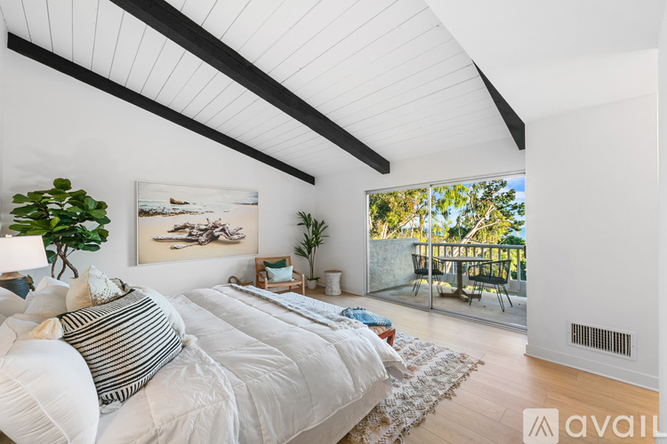 A bedroom with a large bed and a view of the balcony.