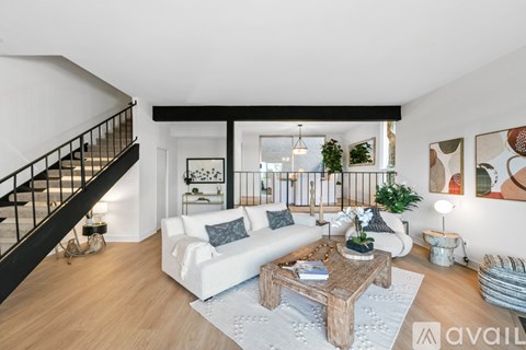 A living room with a staircase on the left and a white couch in the center.