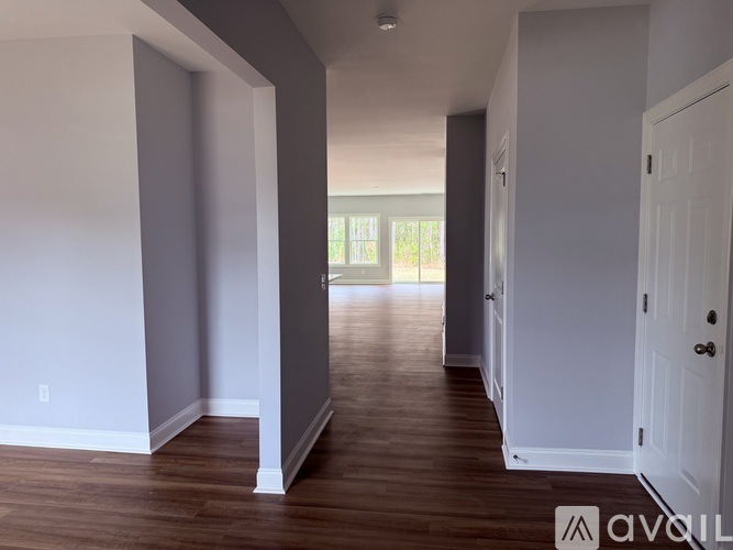 A room with white walls and wooden floors, with a door on the right side.