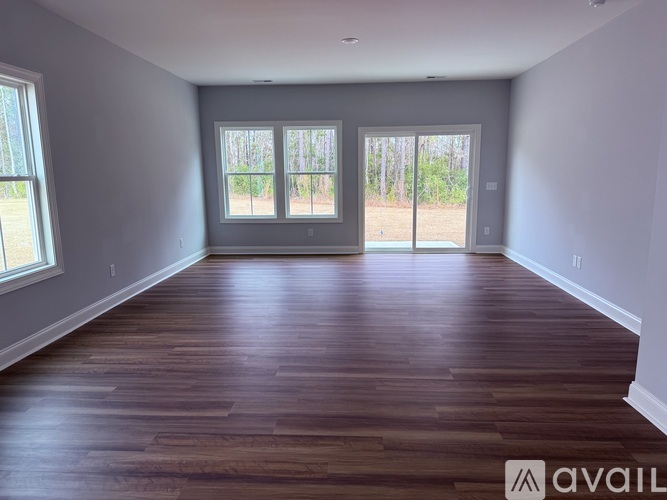 A spacious room with wooden flooring and sliding glass doors.
