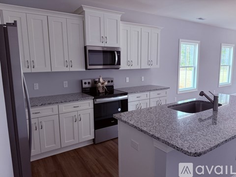 A kitchen with white cabinets and a granite countertop.