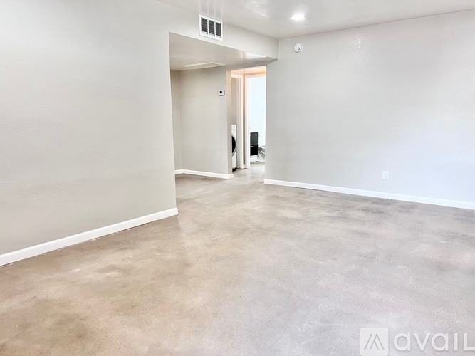 A spacious empty room with a doorway leading to another room.