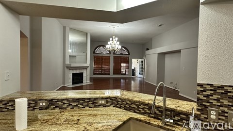A modern kitchen with a marble countertop and a chandelier.