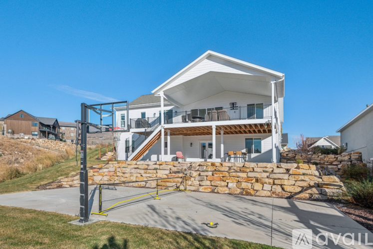 A modern house with a white exterior and a stone wall in the front yard.