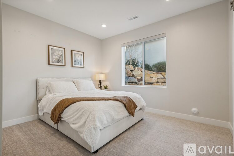 A bedroom with a large bed and two pictures on the wall.