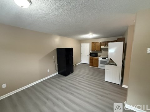 A black refrigerator sits in a kitchen with a microwave and oven.