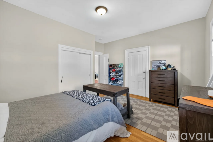 A bedroom with a bed, dresser, and a small table with a lamp.