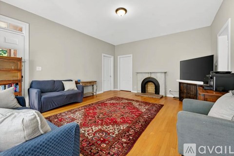 A living room with a fireplace and a rug in the middle.