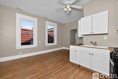 A kitchen with white cabinets and a wooden floor.