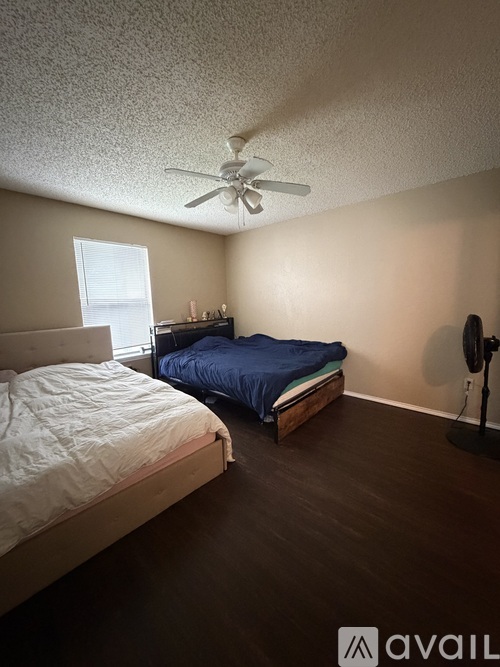 A bedroom with a bed, a bedside table, and a ceiling fan.