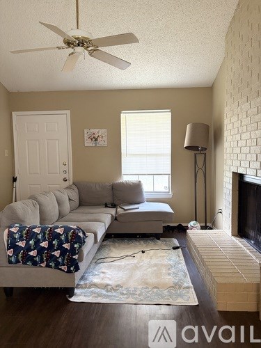 A living room with a grey couch and a fan on the ceiling.