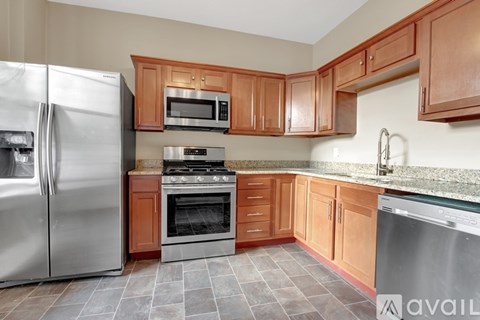 A kitchen with wooden cabinets and a stainless steel refrigerator.