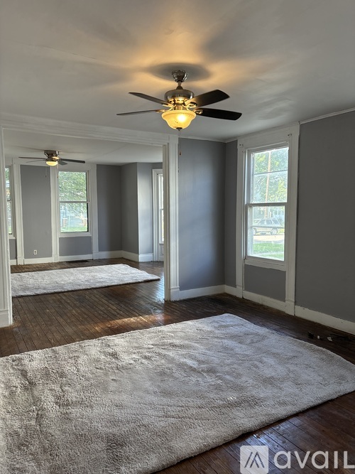 A room with a ceiling fan and a rug on the floor.